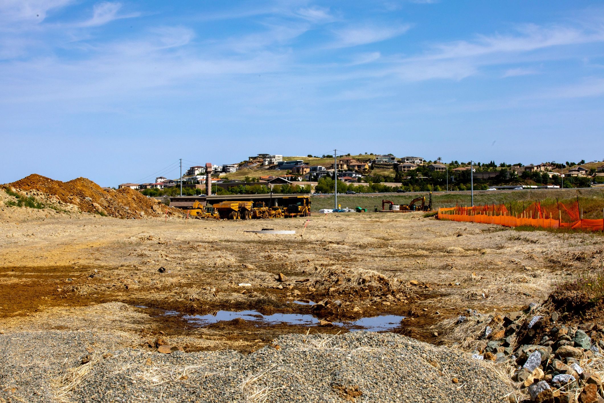 Cleared lot being prepared for development with equipment in the distance