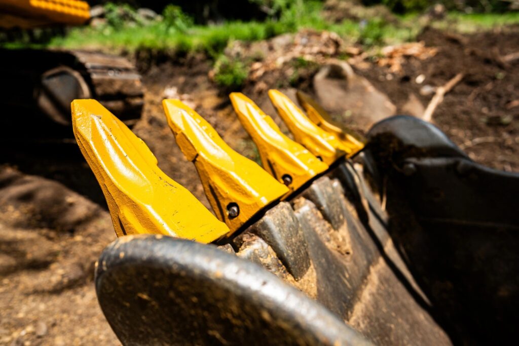 Close-up of a construction vehicle bucket with soil residue on its surface, showing signs of recent use
